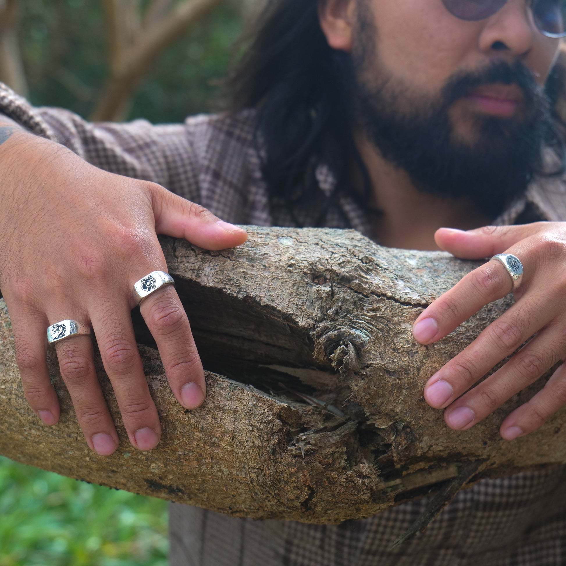 Man holding onto tree branch wearing panther + serpent + bee rings.